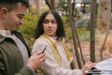 American couple at table with textbooks with smartphones
